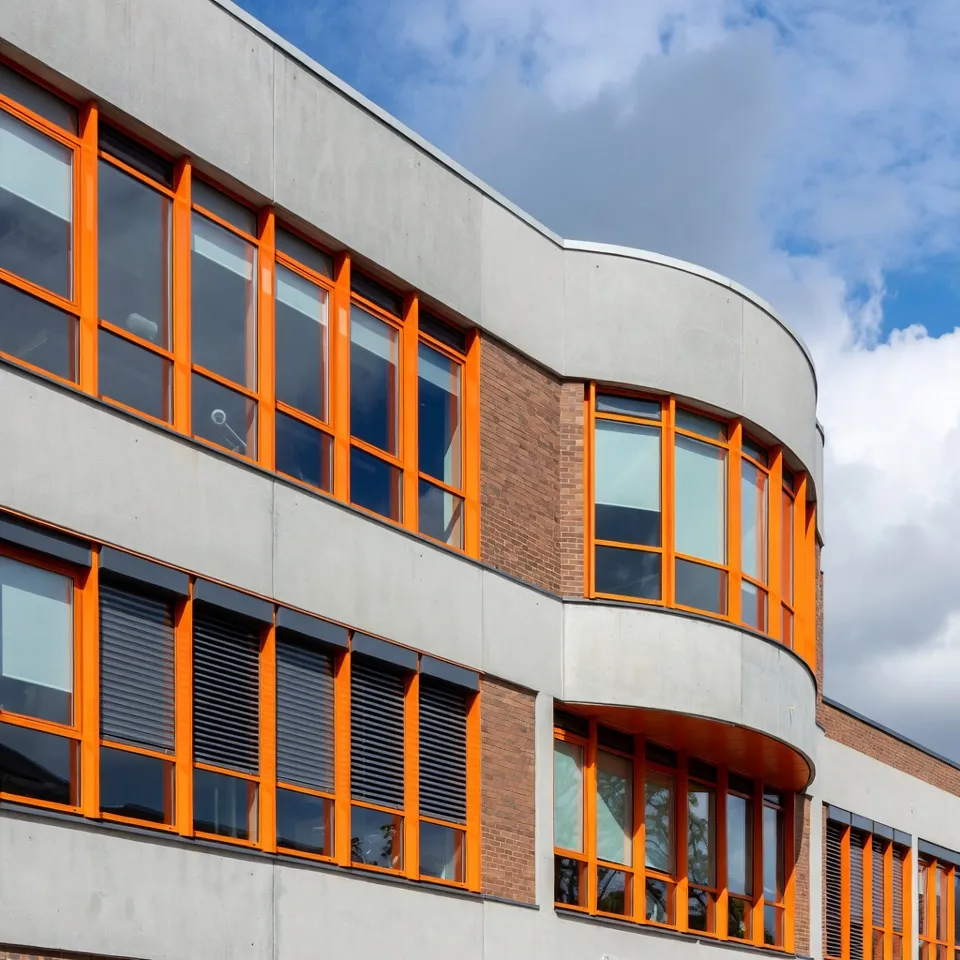 Building facade with orange window frames and curved front section.